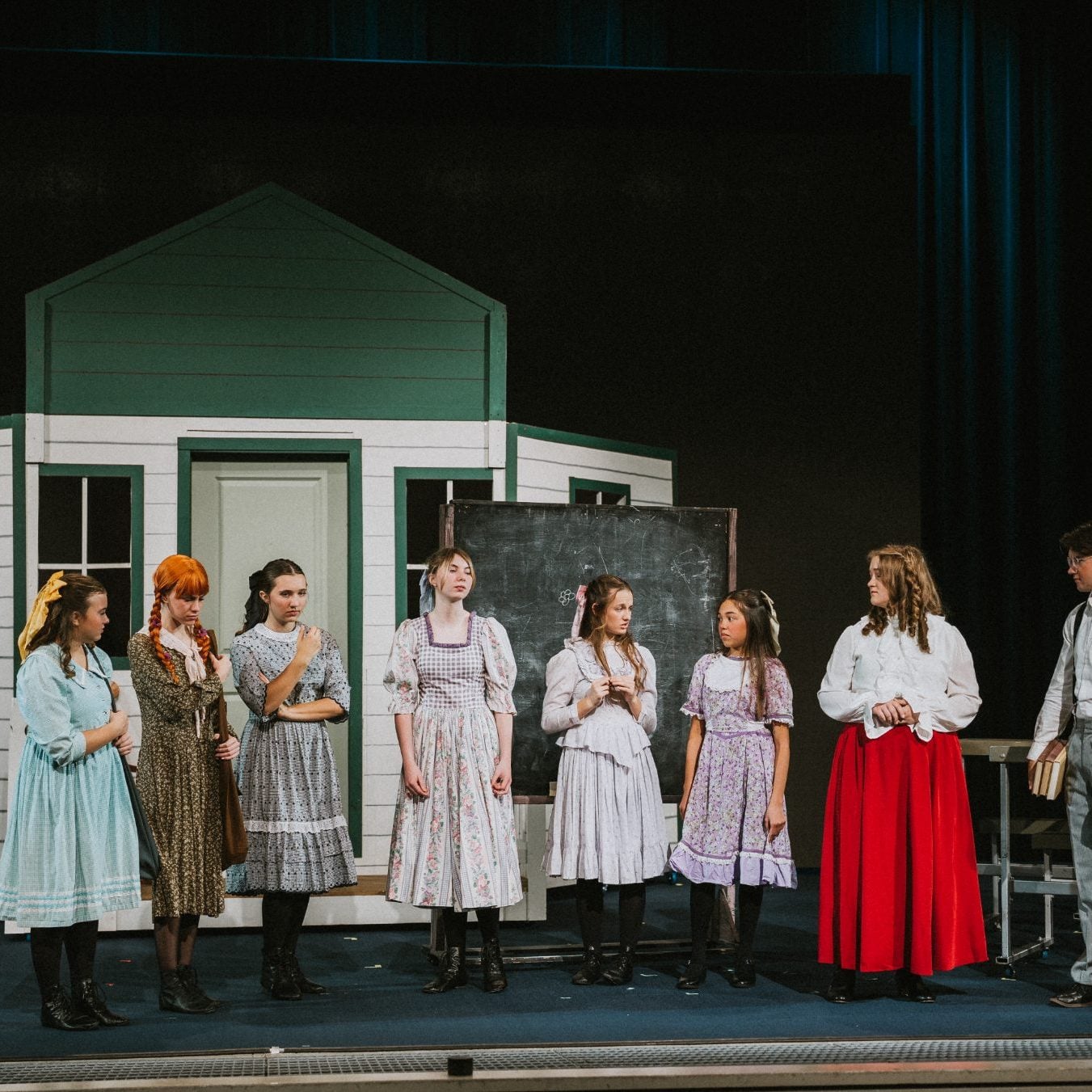 Full cast lines up on stage in front of the schoolhouse set at Shadow Mountain Event Center
