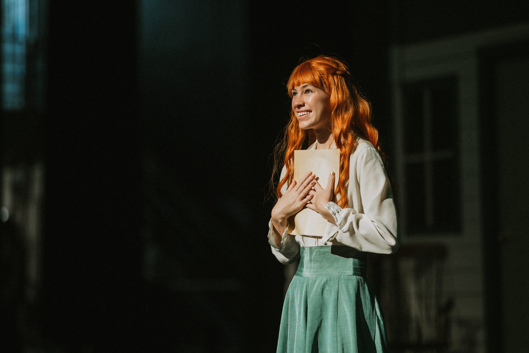 A red-haired student clasps her hands during an emotional stage moment