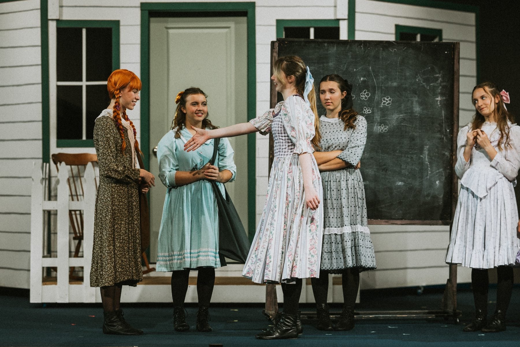Students comfort a castmate near a chalkboard during Anne of Green Gables