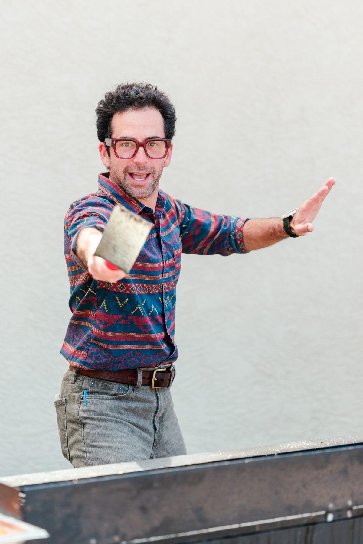 A chef in a patterned shirt tossing a spatula at the BBQ