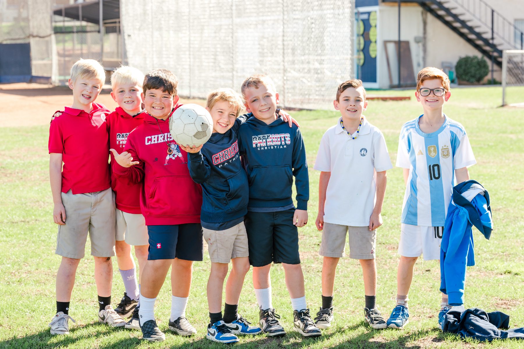 A second group of six boys pose with a soccer ball outside
