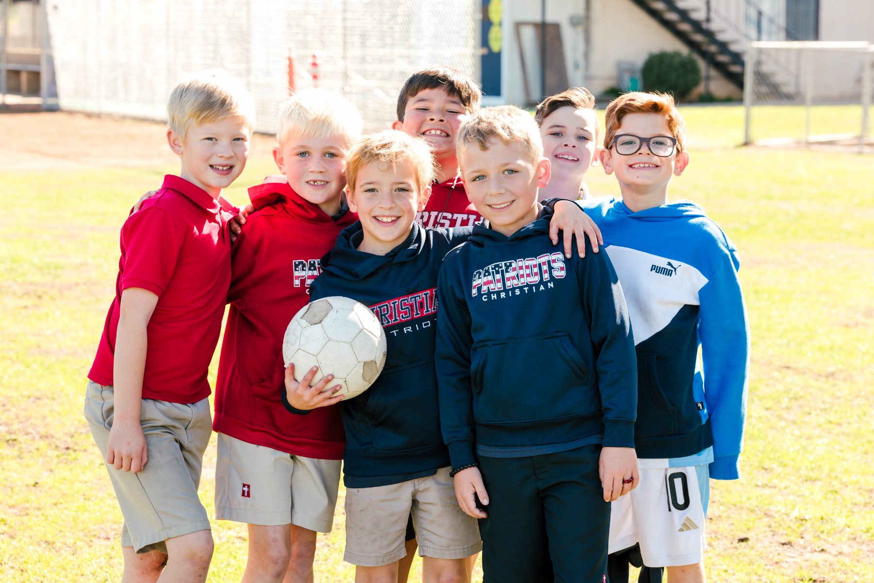 Six boys pose together holding a soccer ball on the field