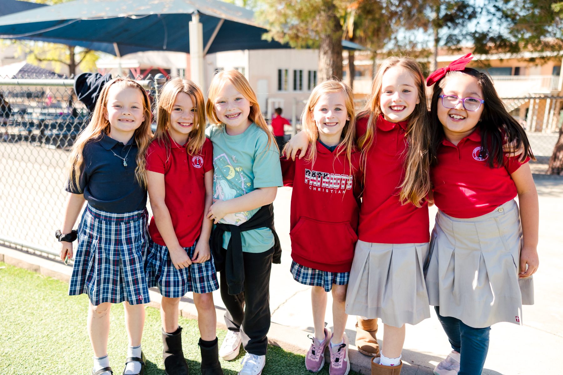 Six smiling students in uniform gather outside at Christian Elementary School
