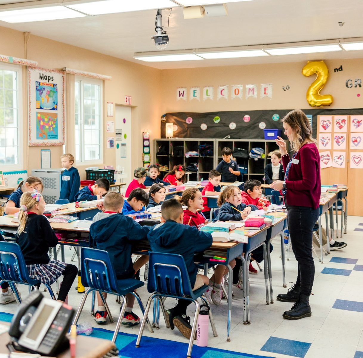 A teacher leads a lesson to second graders in a bright classroom