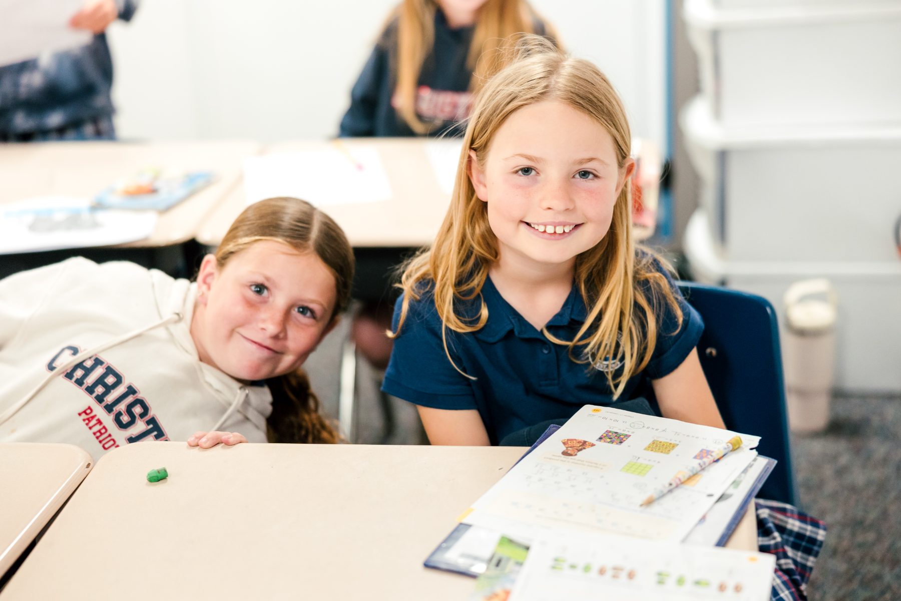 Two smiling students share a desk during class at Christian Elementary School