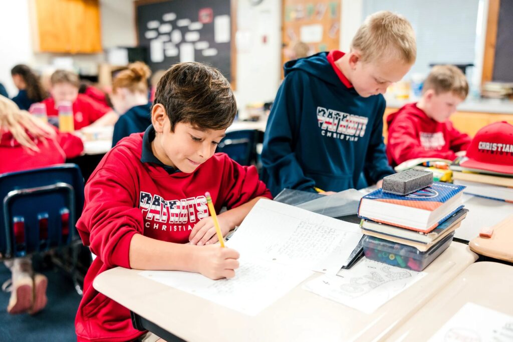 Students writing in notebooks at their desks in a Christian Elementary classroom