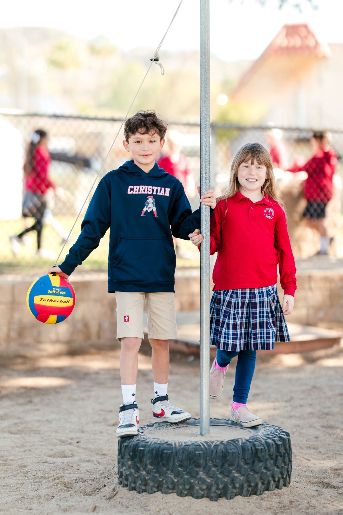Two Christian Elementary students stand by the tetherball pole on the playground
