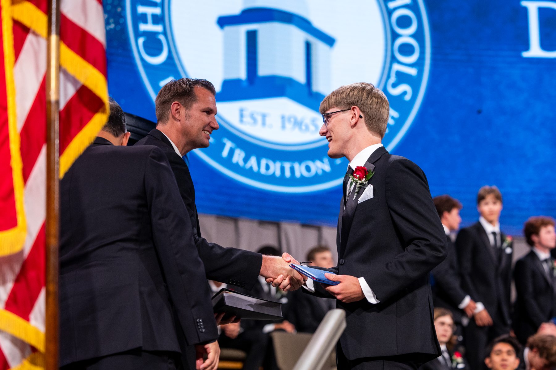 A teacher hands a diploma to a graduate on stage at Shadow Mountain Community Church