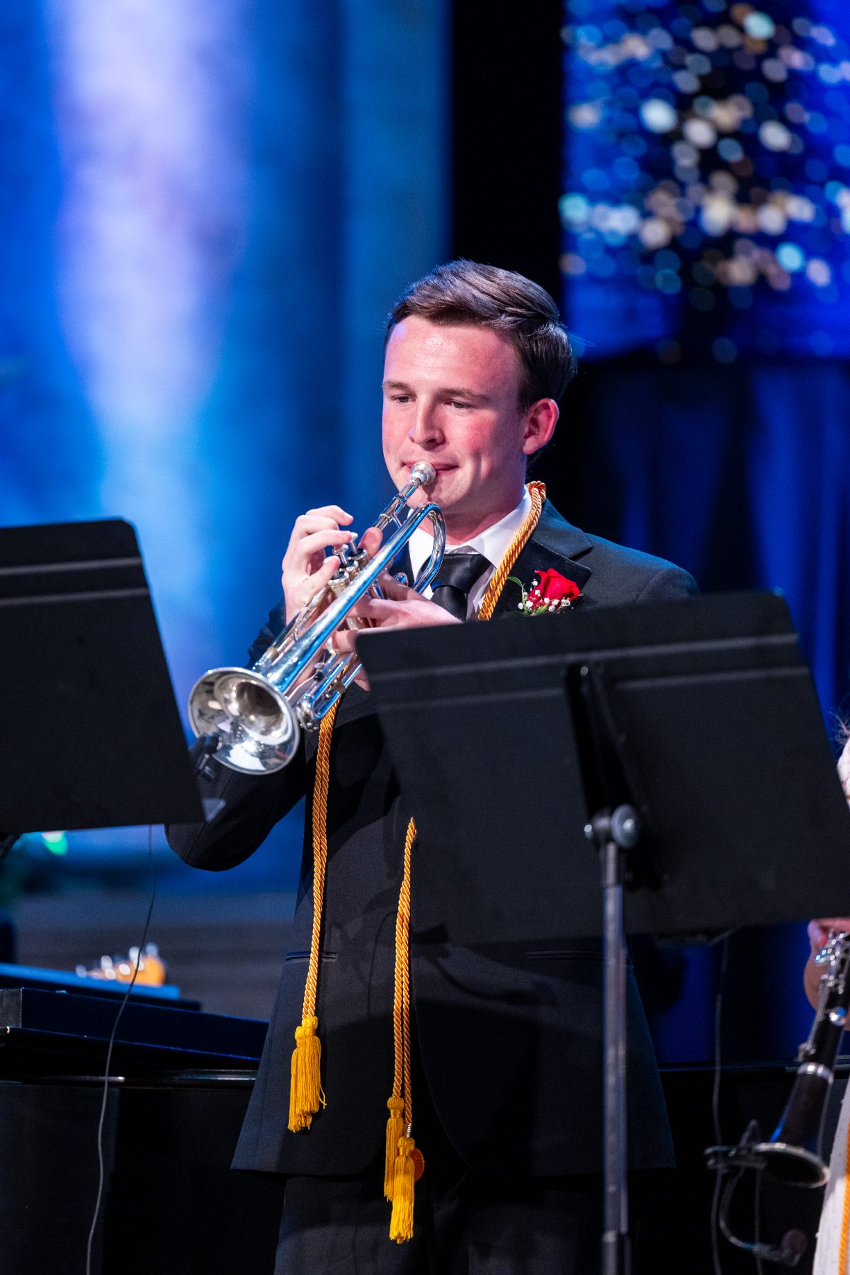 A student in a red jacket plays trumpet during the Christian high school graduation ceremony