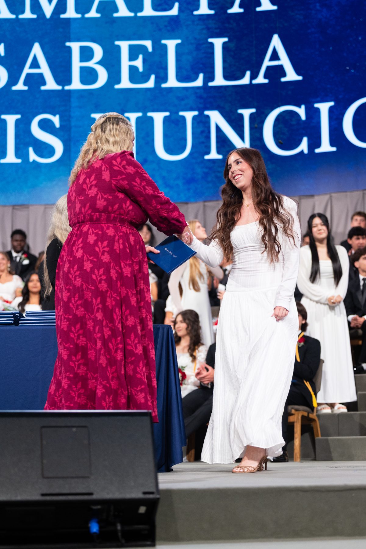 A staff member congratulates a Christian High School graduate crossing the stage.