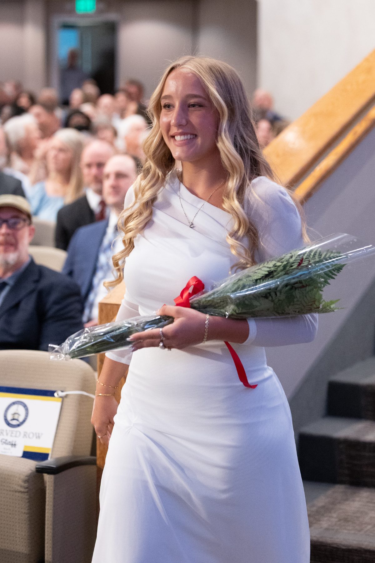 A Christian High School graduate carries flowers down the aisle after commencement.