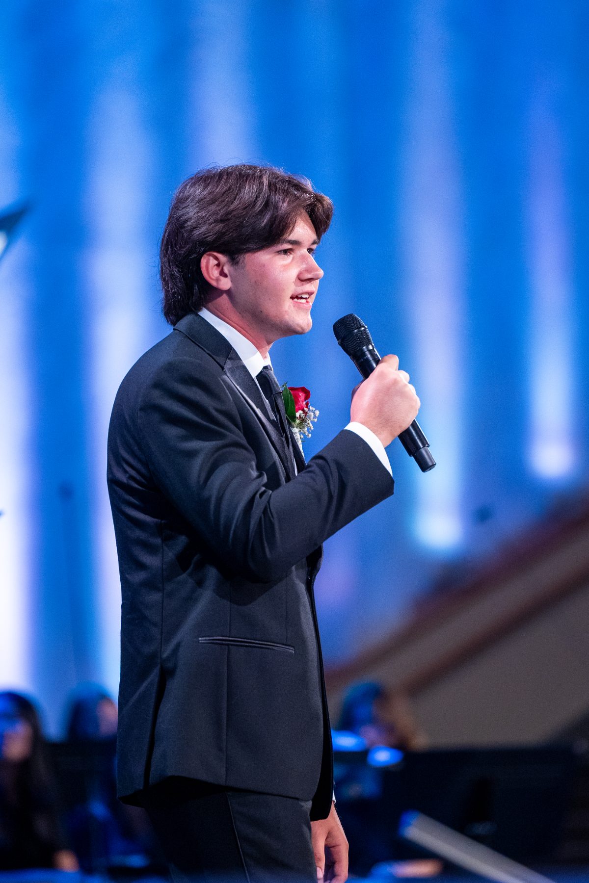 A young man sings into a microphone at Christian High School Patriots graduation.