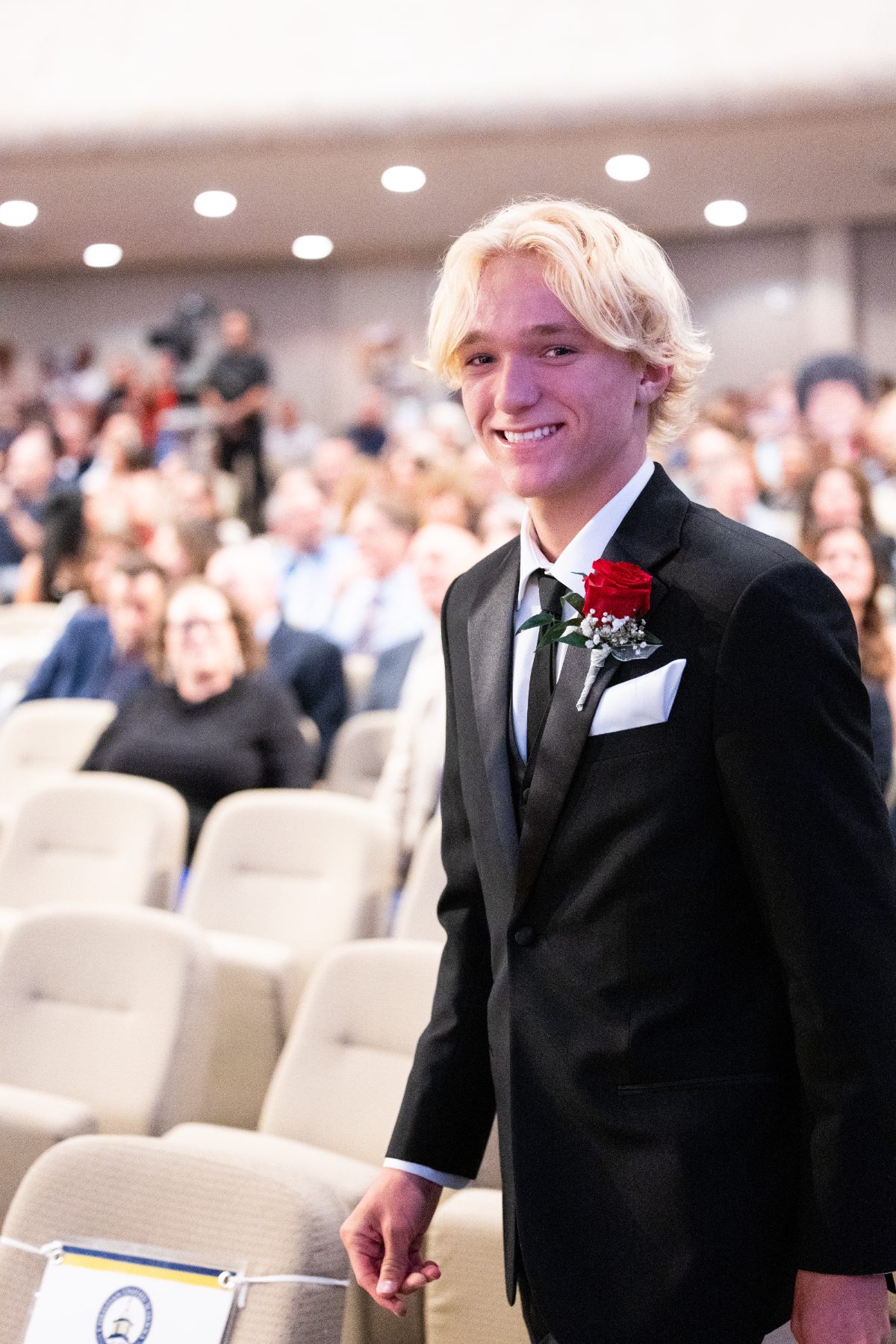 Christian High School Patriots graduate smiles while walking through auditorium at graduation