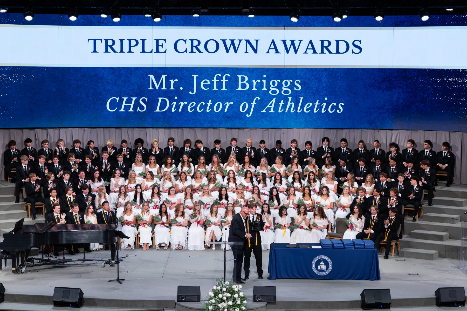 Christian High School athletics director addresses graduates under Triple Crown Awards banner.
