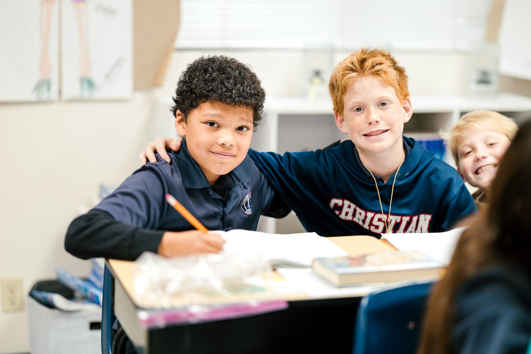 Two junior high students share a laugh together at their classroom desk