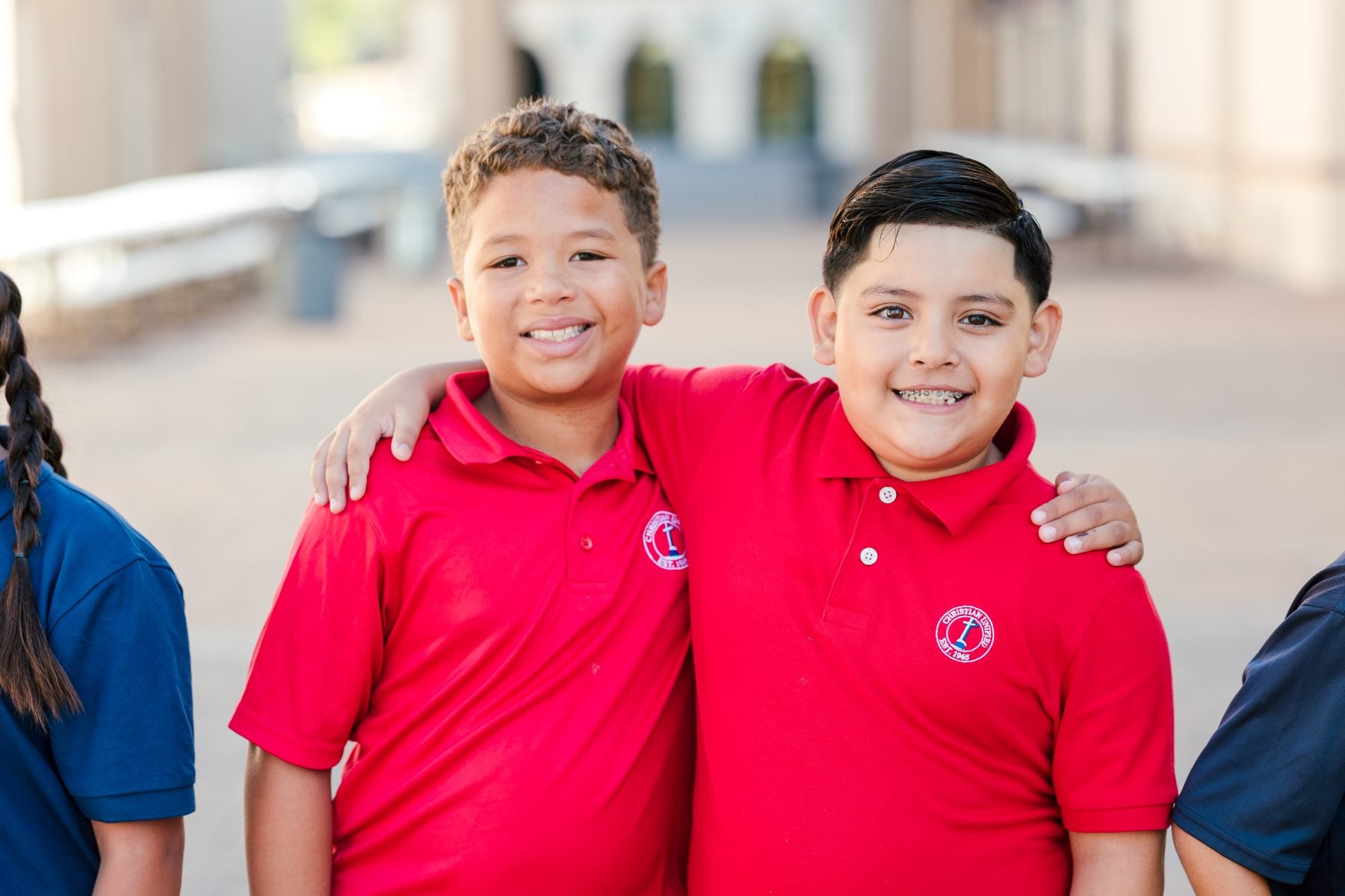 Two Christian Unified Schools students in red polos smile outdoors on the first day