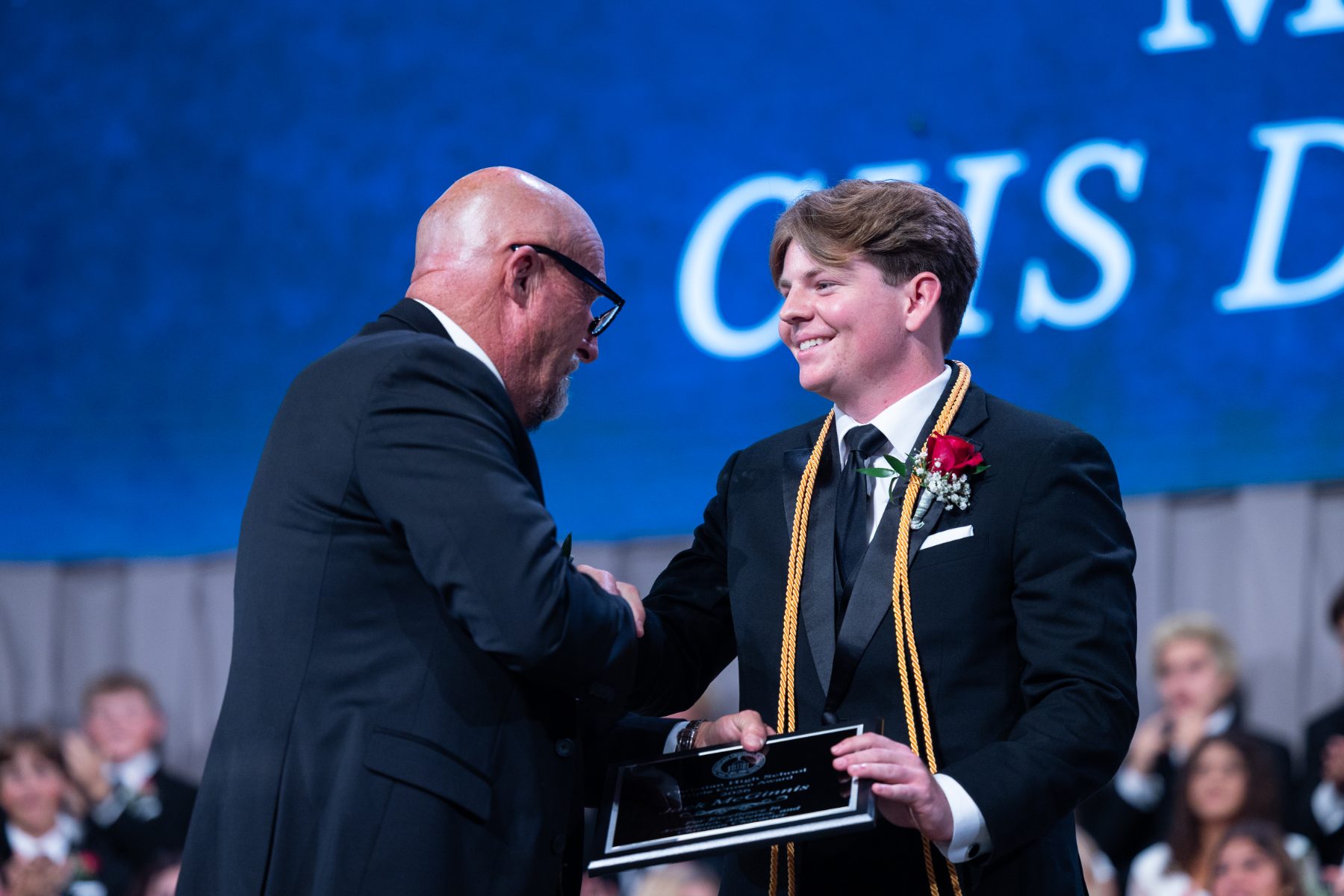 A graduate shakes hands with an administrator while receiving a CHS diploma award