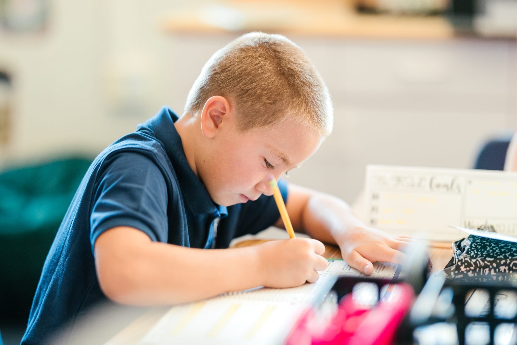Elementary student writes carefully in notebook during first day of school