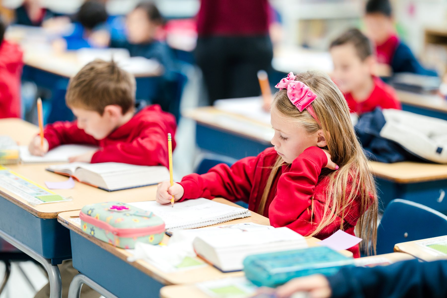 A girl focuses on writing in her notebook during class at Christian Elementary School