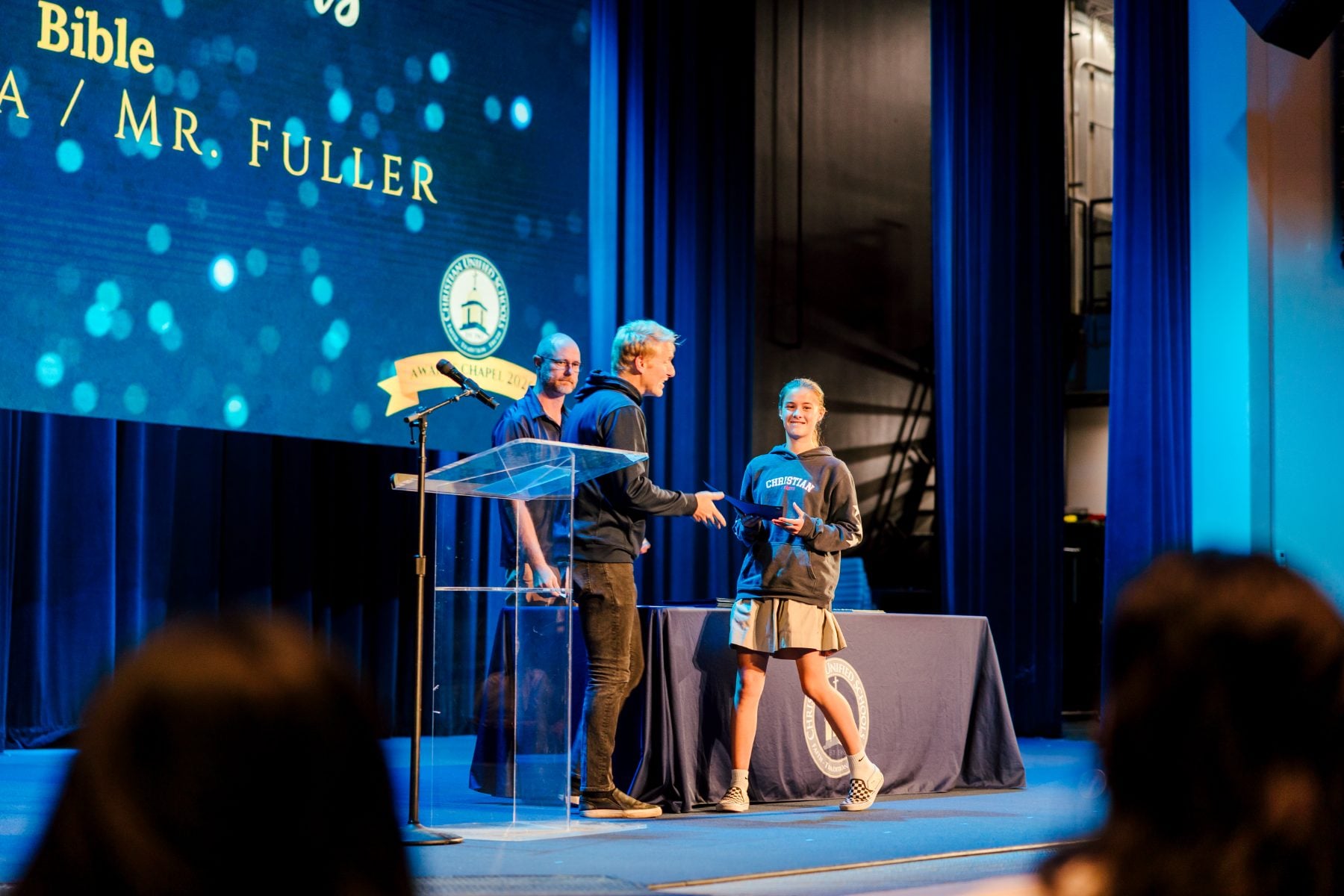 A teacher shakes a student's hand after presenting the Bible award.