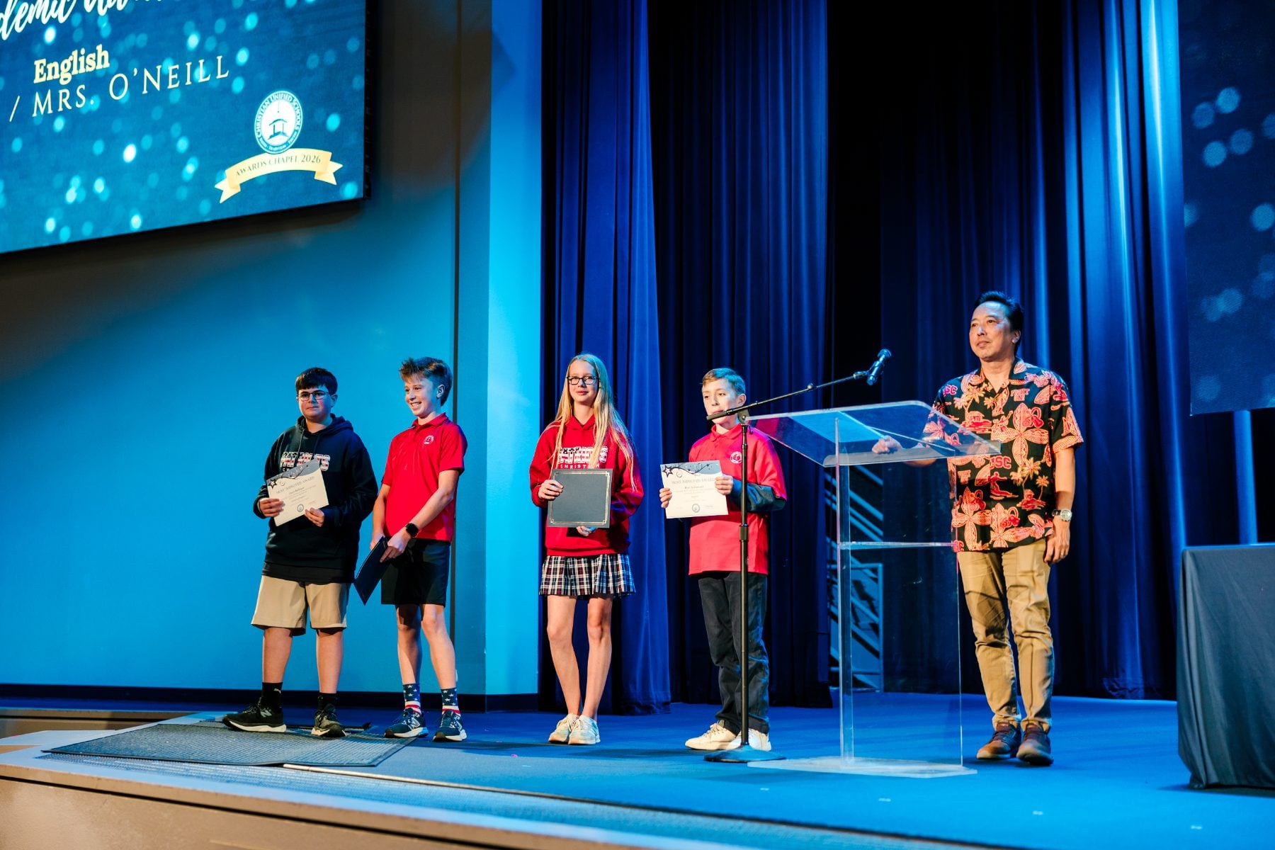 Five students and a teacher gather at the podium for English department awards.