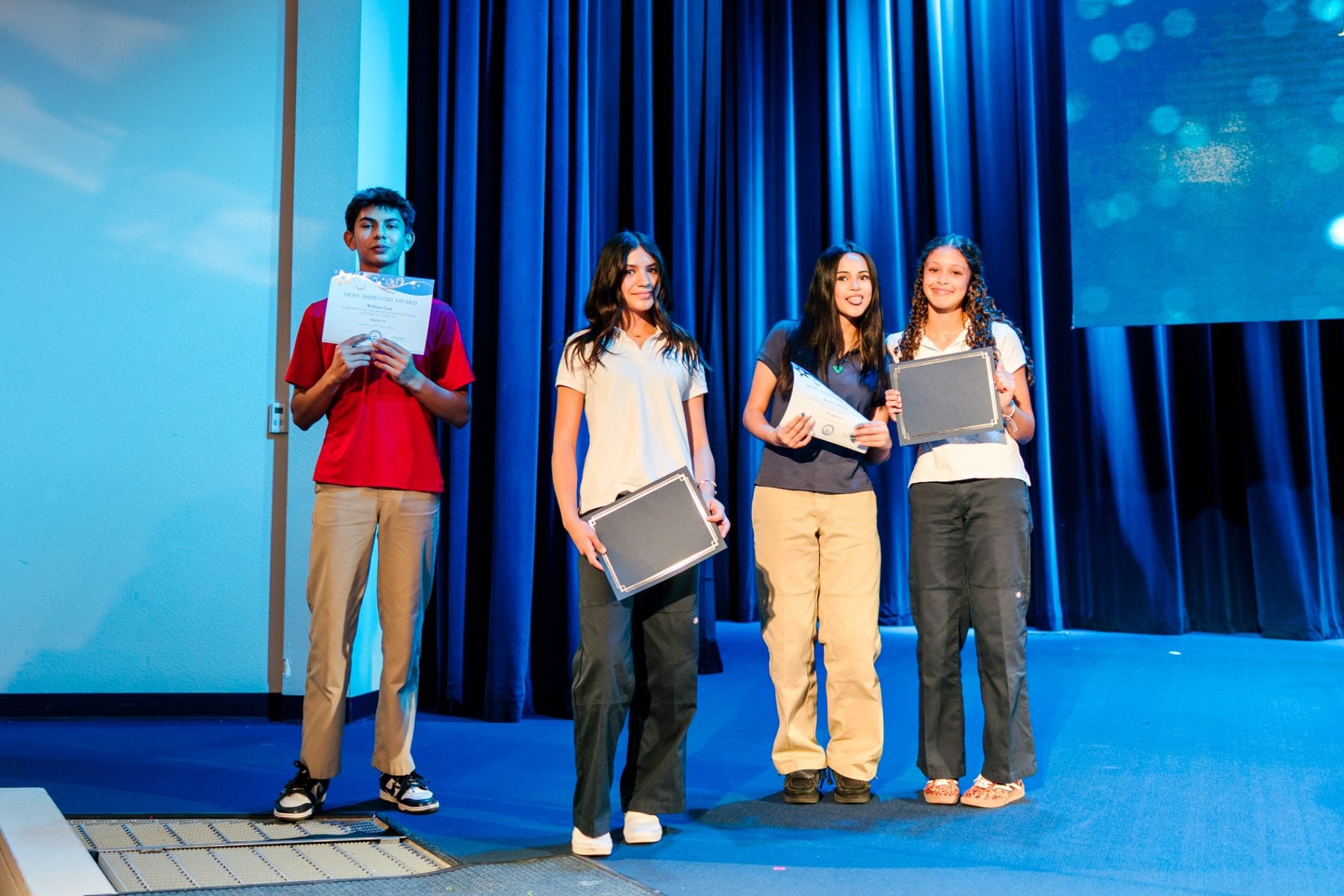 Four junior high students stand holding certificates during the awards chapel ceremony.
