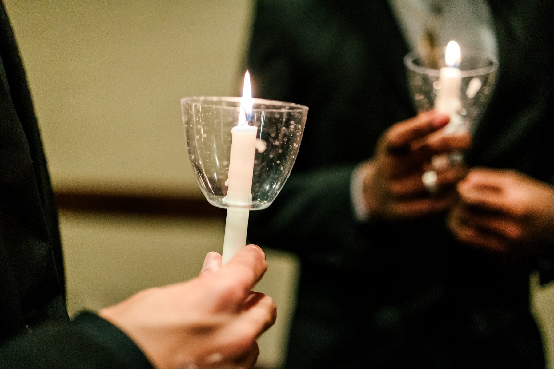 Close-up of students' hands holding lit candles at the ceremony