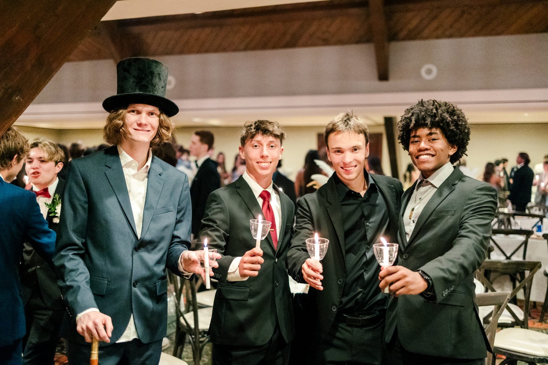 Four students in suits raise sparkling glasses at the banquet