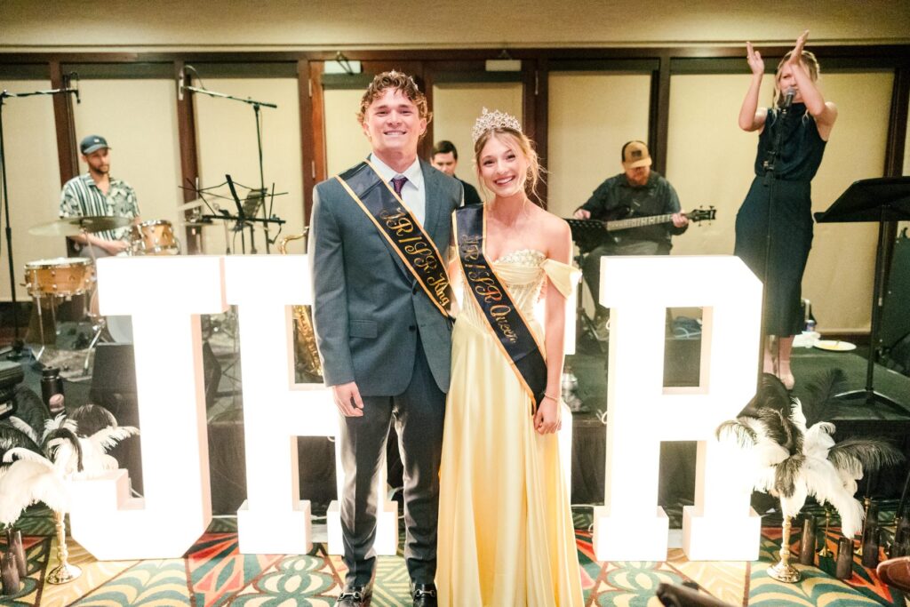 Jr/Sr Banquet king and queen pose beside large JRSR letters