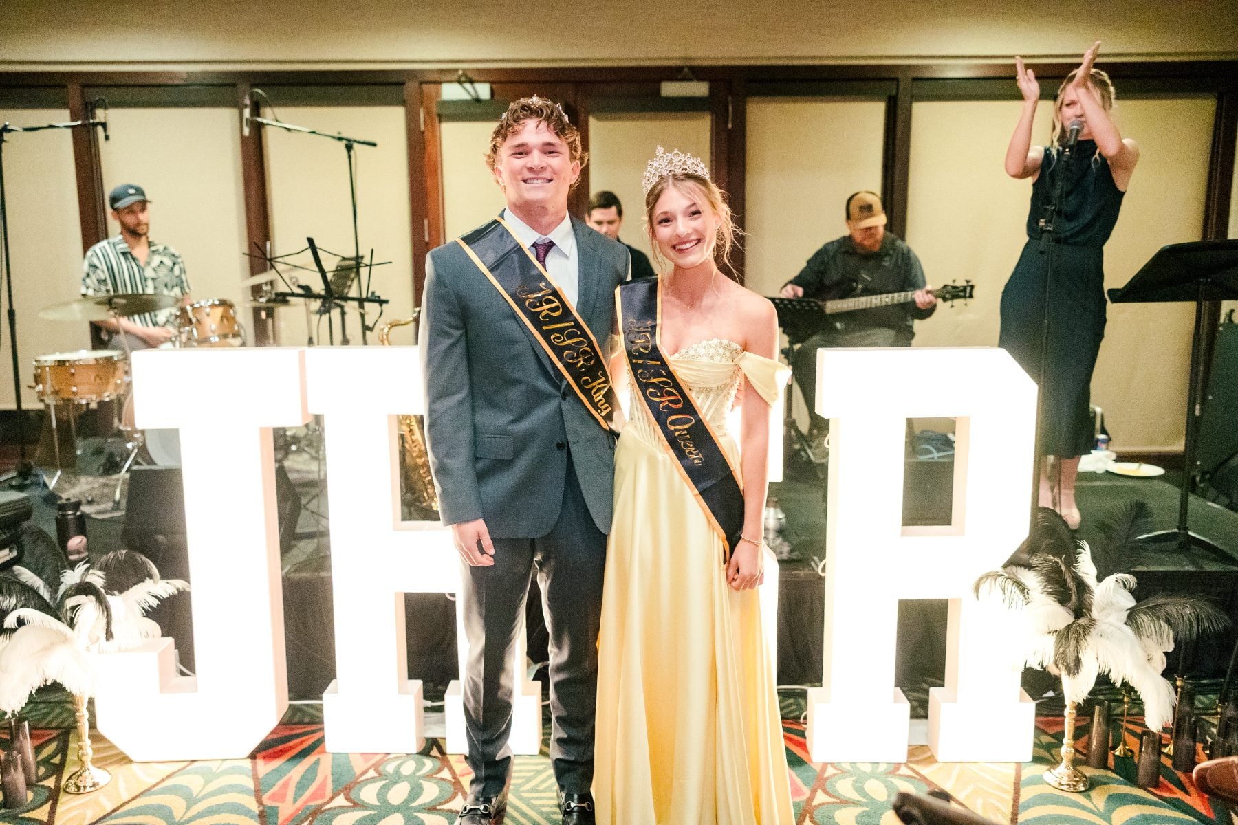 Jr/Sr Banquet king and queen pose beside large JRSR letters