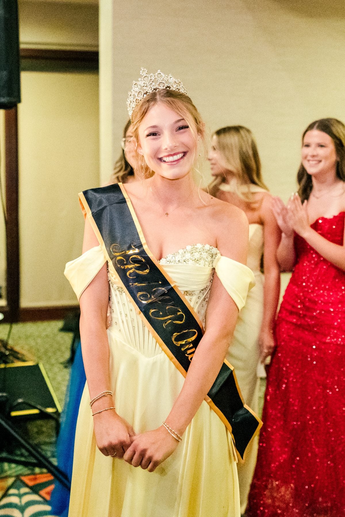 Crowned queen nominee smiles in yellow gown at Jr/Sr Banquet, Catamaran Resort