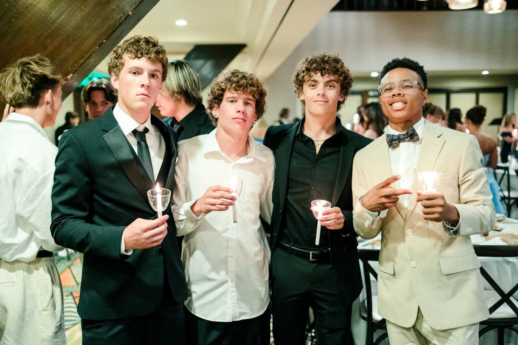 Four students in formal wear hold candles during the banquet