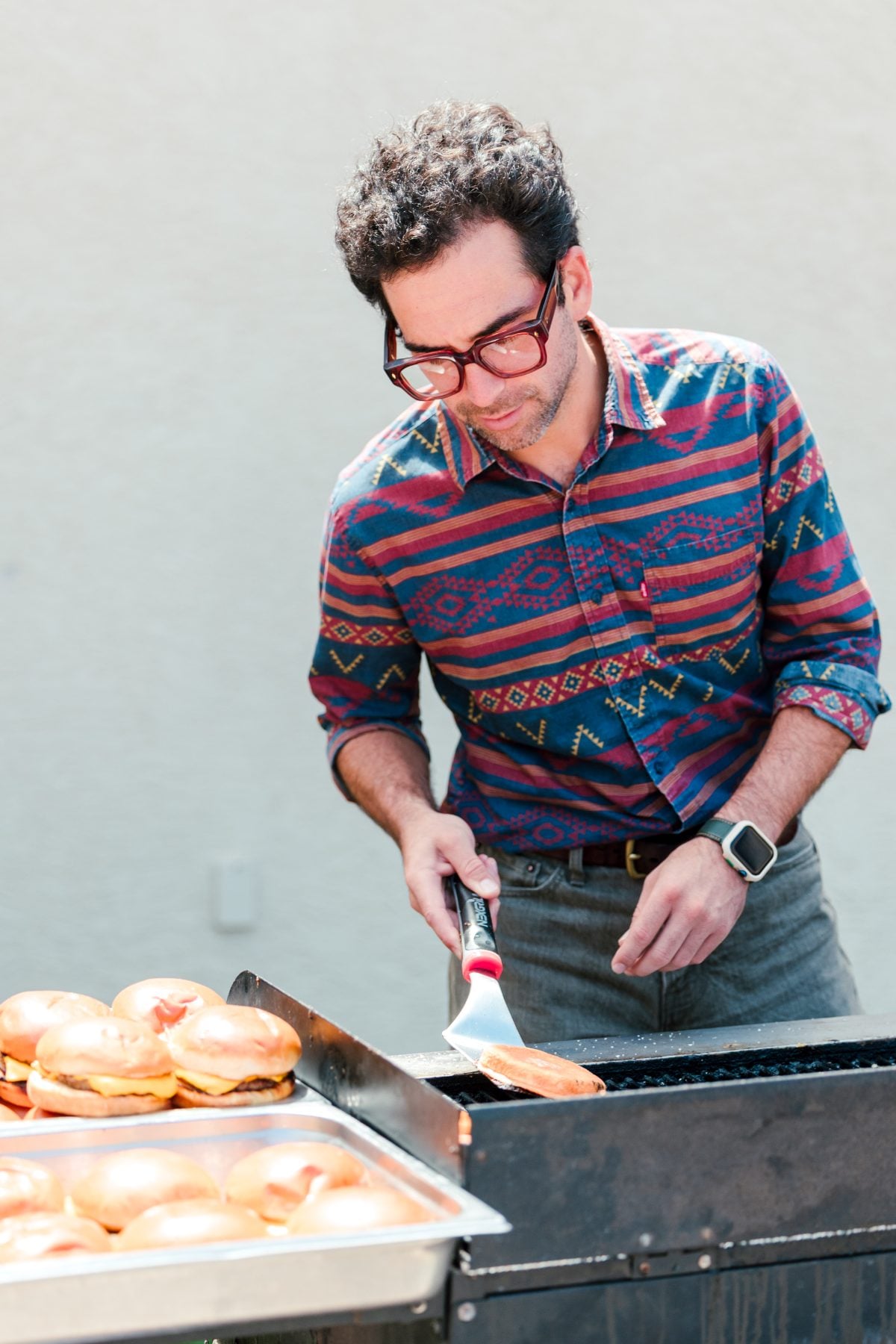 A man grilling burger buns on a griddle at the school BBQ