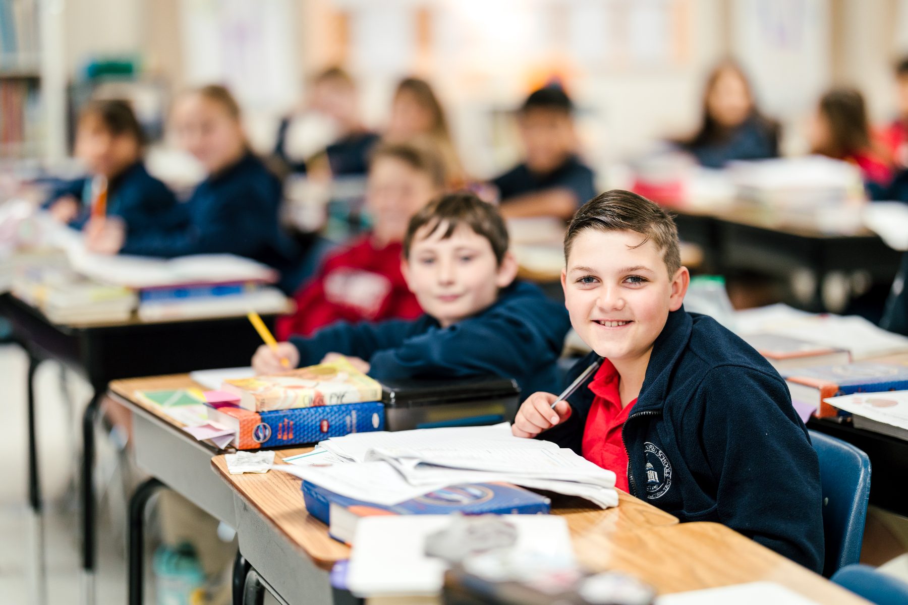 A student smiles at his desk during class at Christian Elementary School