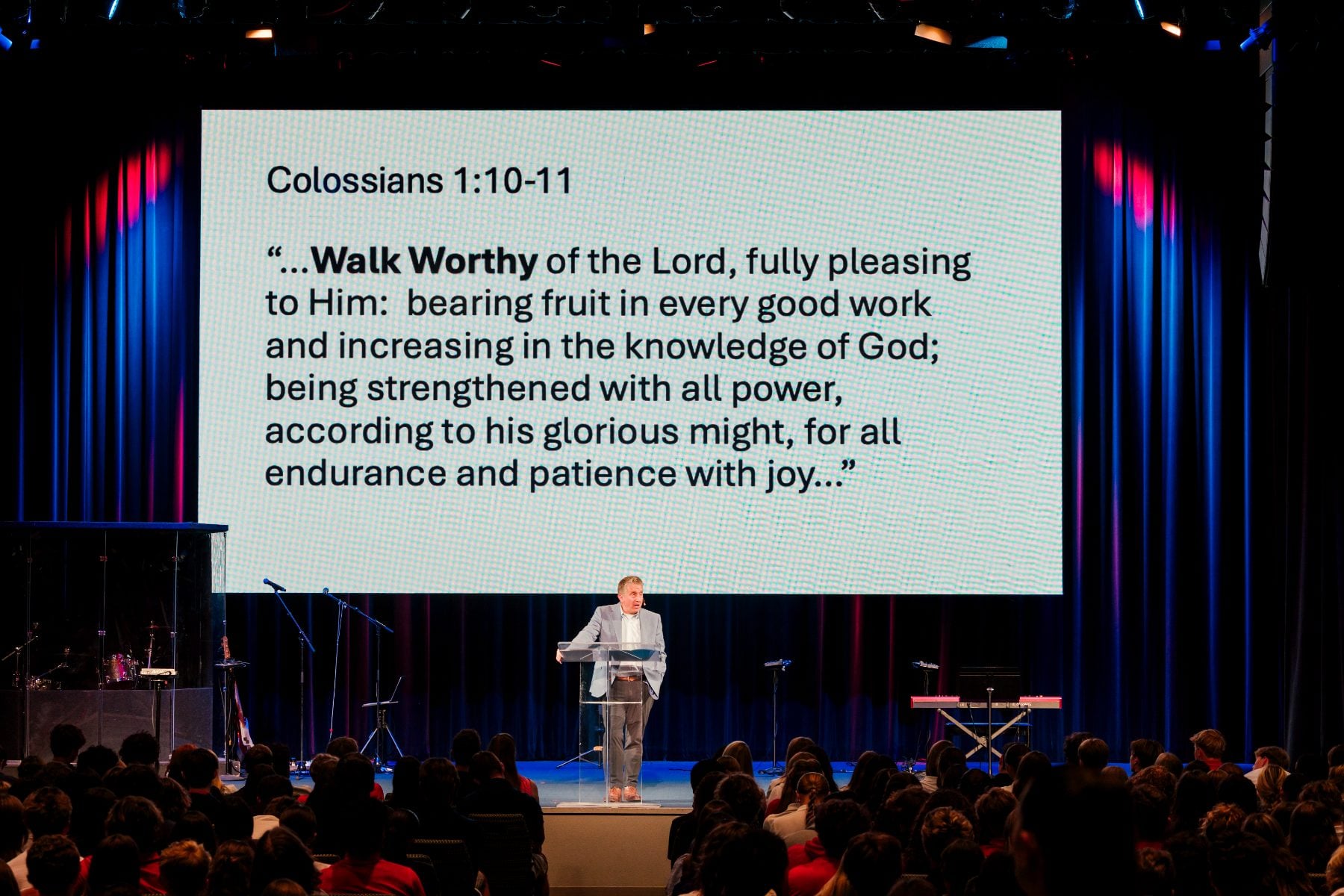 A speaker addresses the crowd beside a Colossians 1:10-11 Walk Worthy slide