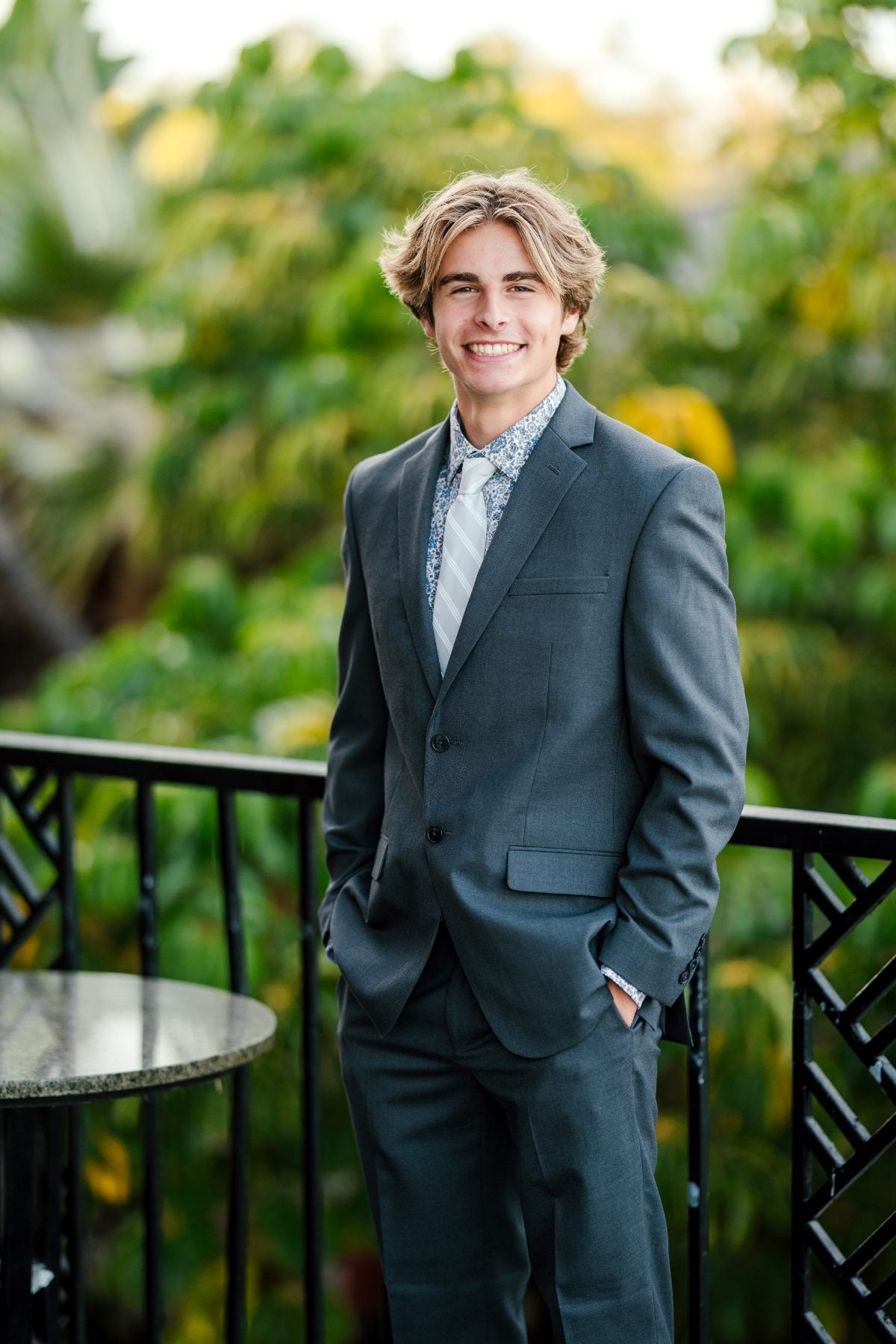 Student in gray suit smiles on balcony at Catamaran Resort