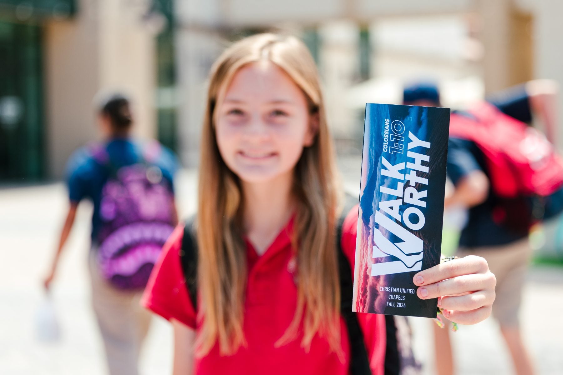 Student at Christian Unified Schools holds a Walk Worthy chapel booklet outside