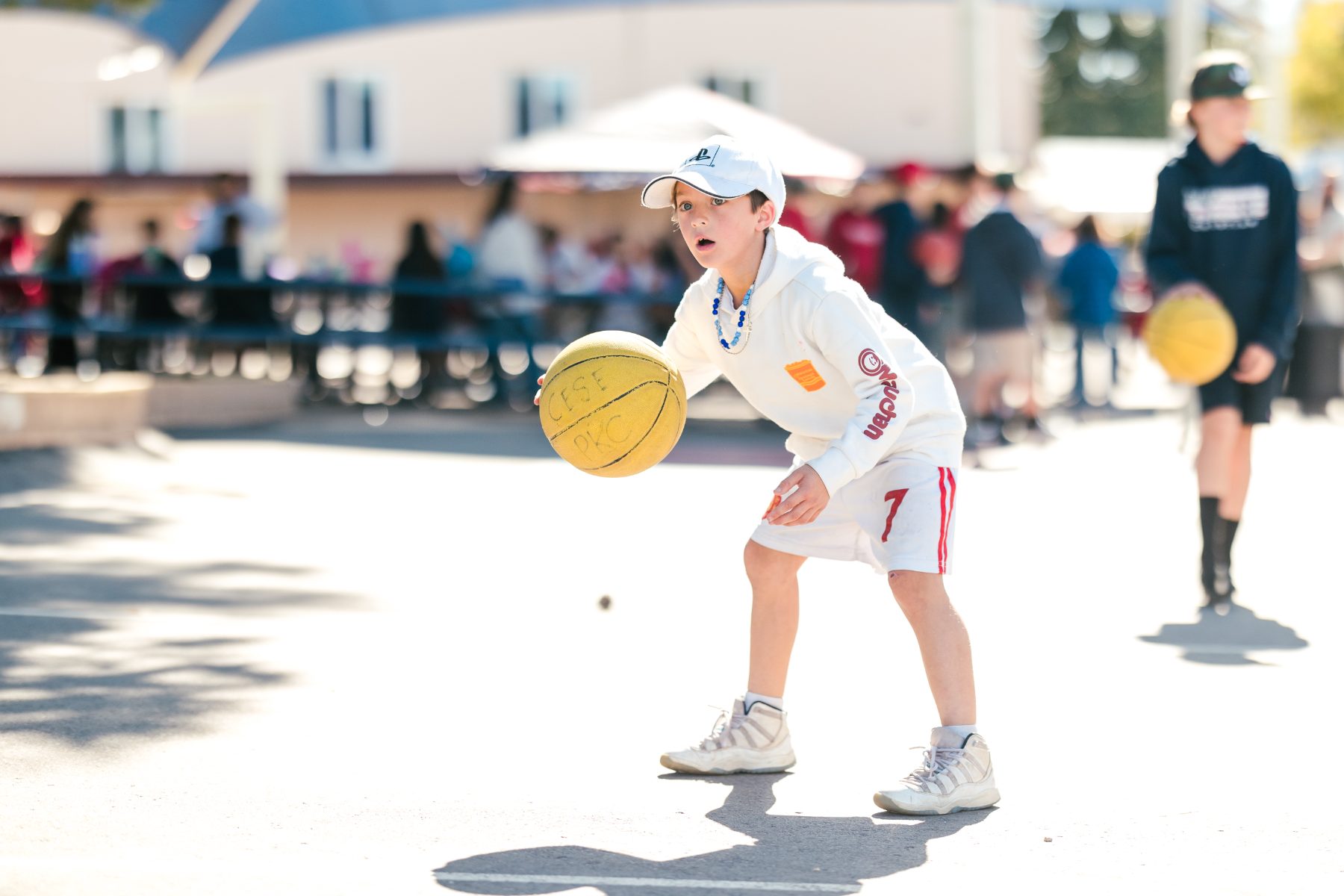 A boy dribbles a basketball outdoors at a Christian elementary campus event