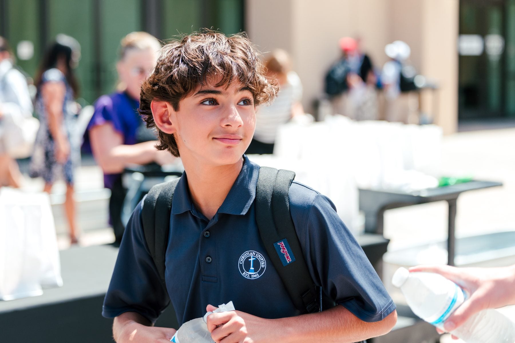 A student smiling while holding a water bottle at the event