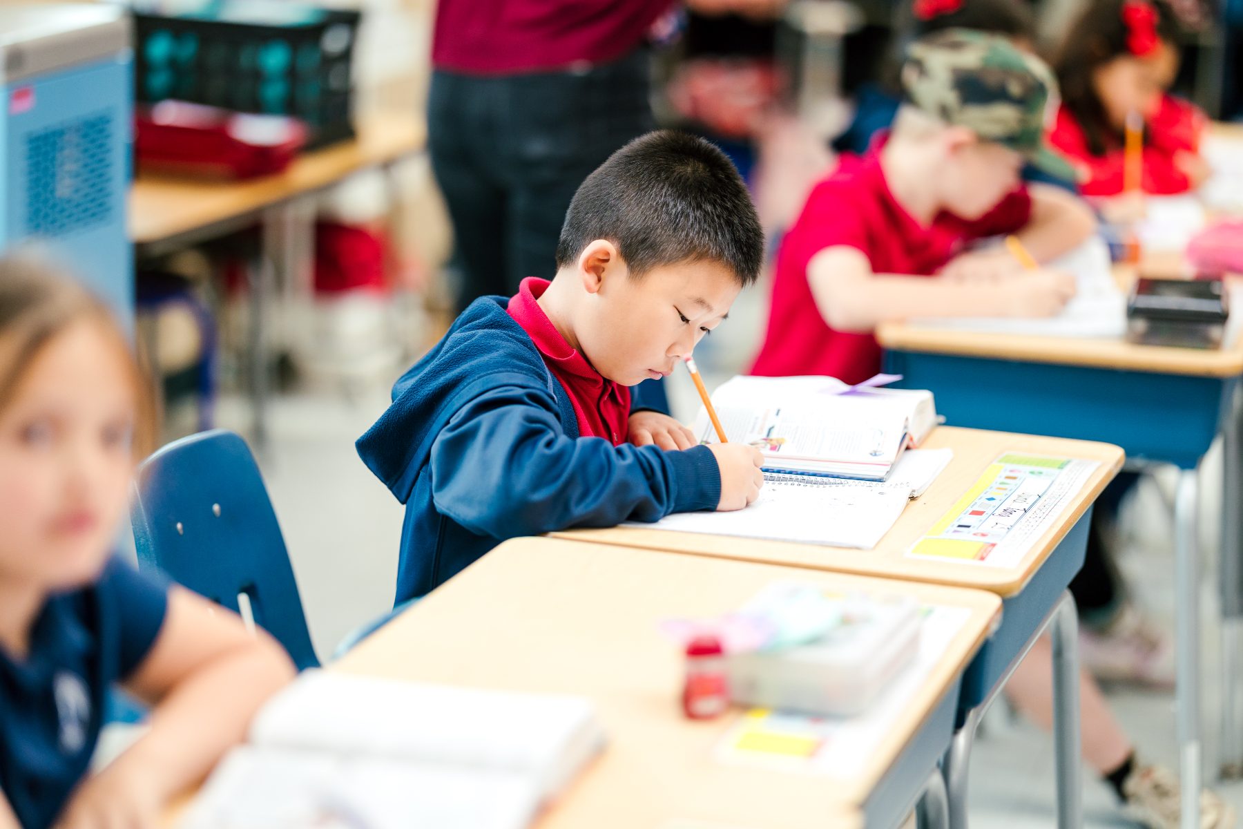 A student concentrates while writing in his workbook in class