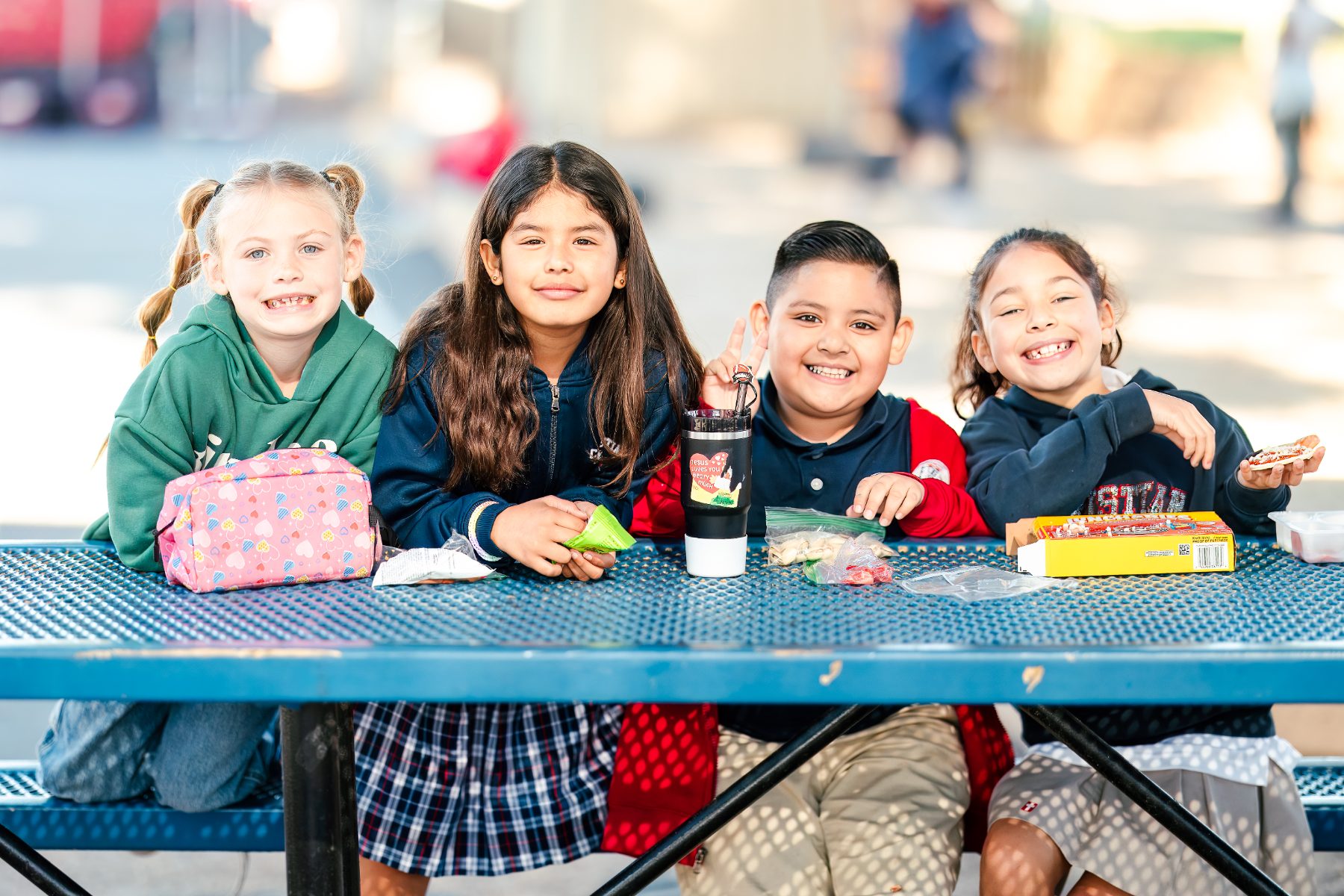 Four students share lunch together at a picnic table on campus