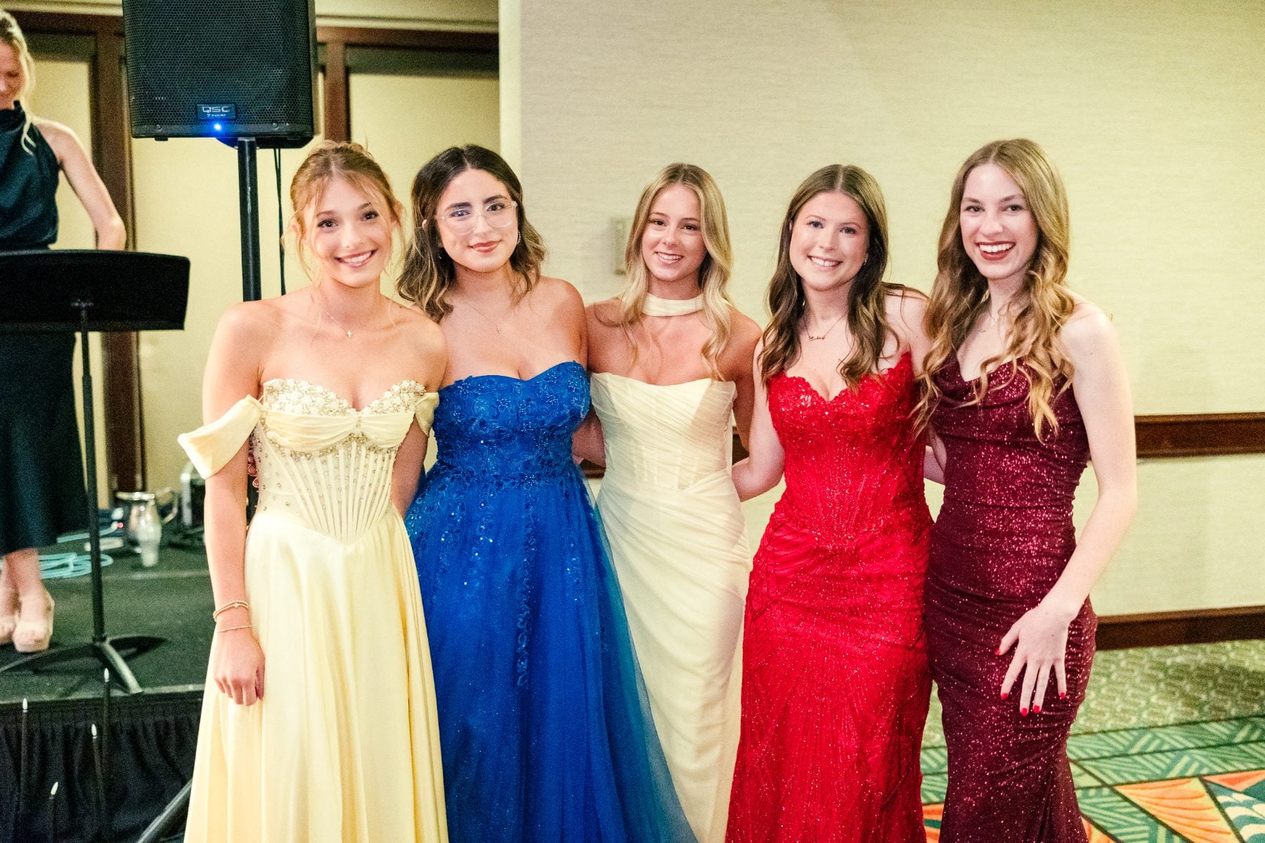 Five students pose together in colorful formal gowns at the banquet