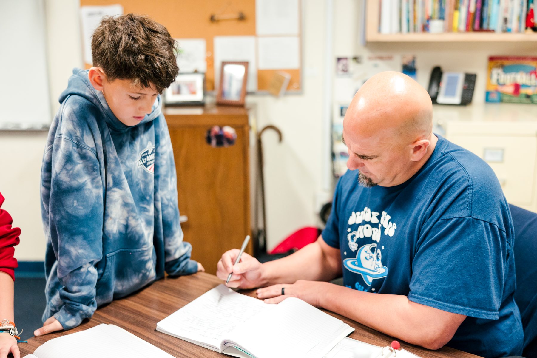 A teacher helps a student with schoolwork at a classroom table