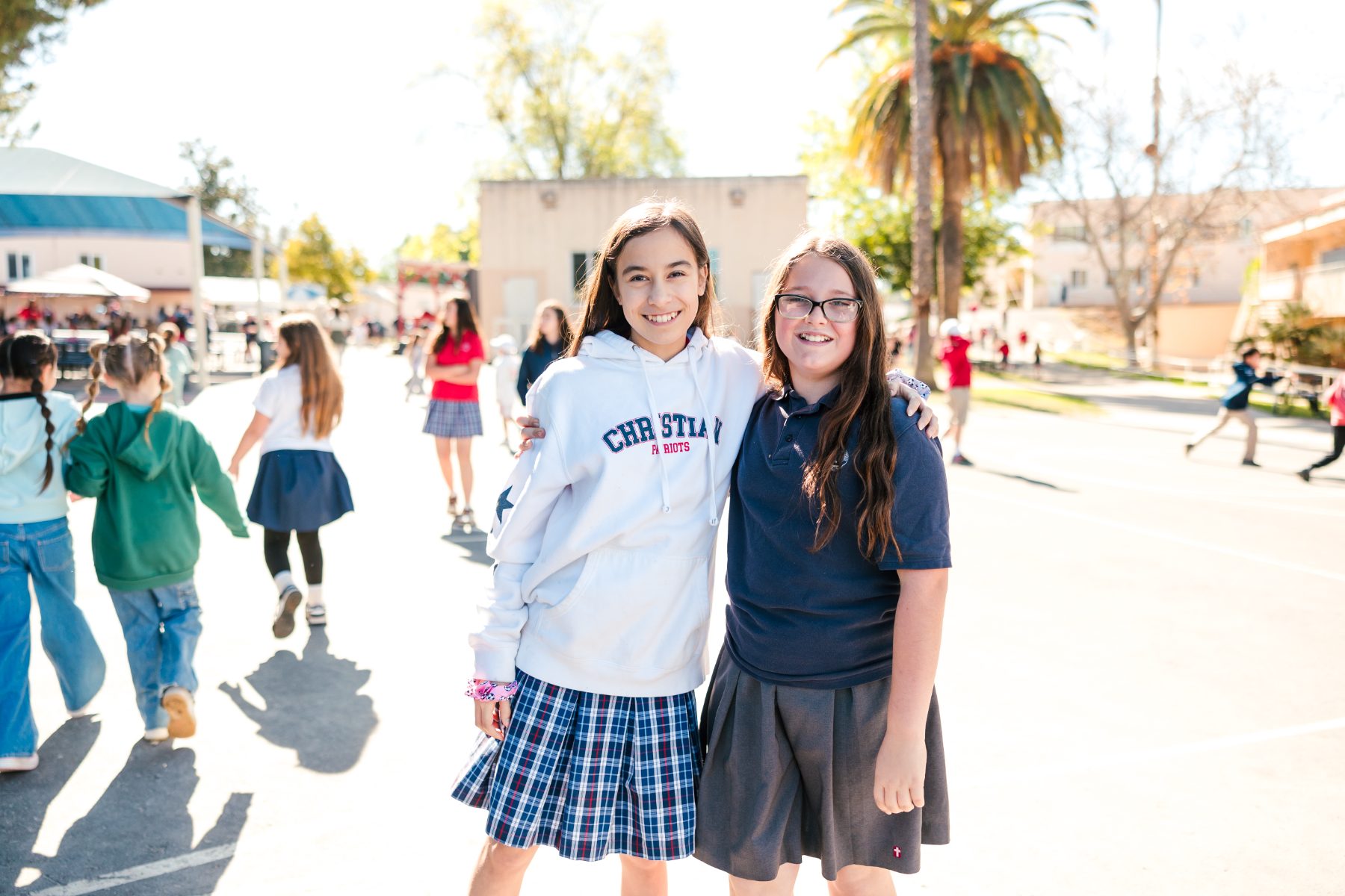 Two students in uniform smile together on the Christian Elementary campus