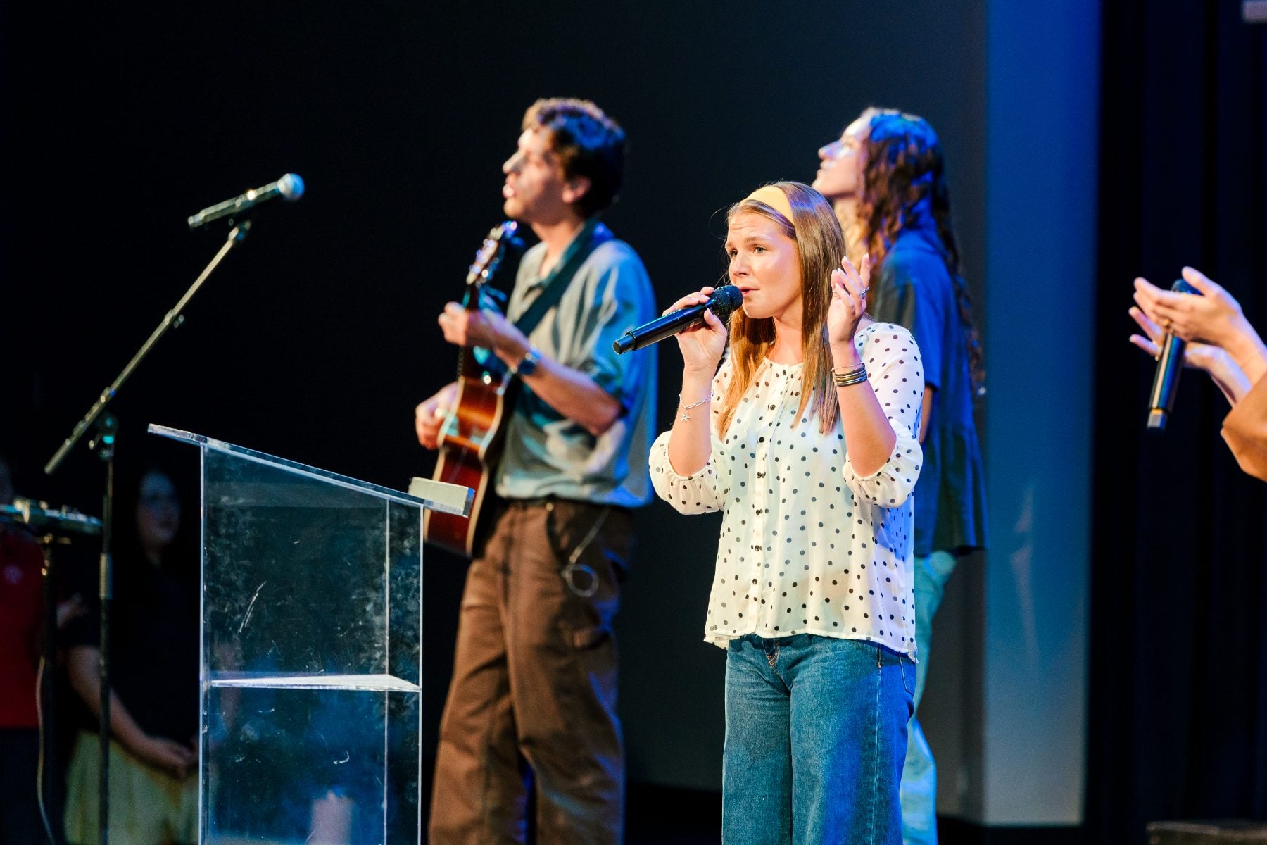 Worship team sings into microphones on stage at the chapel event