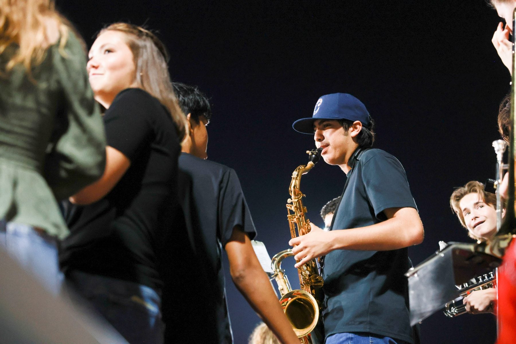 A student plays saxophone with the band during the Homecoming game