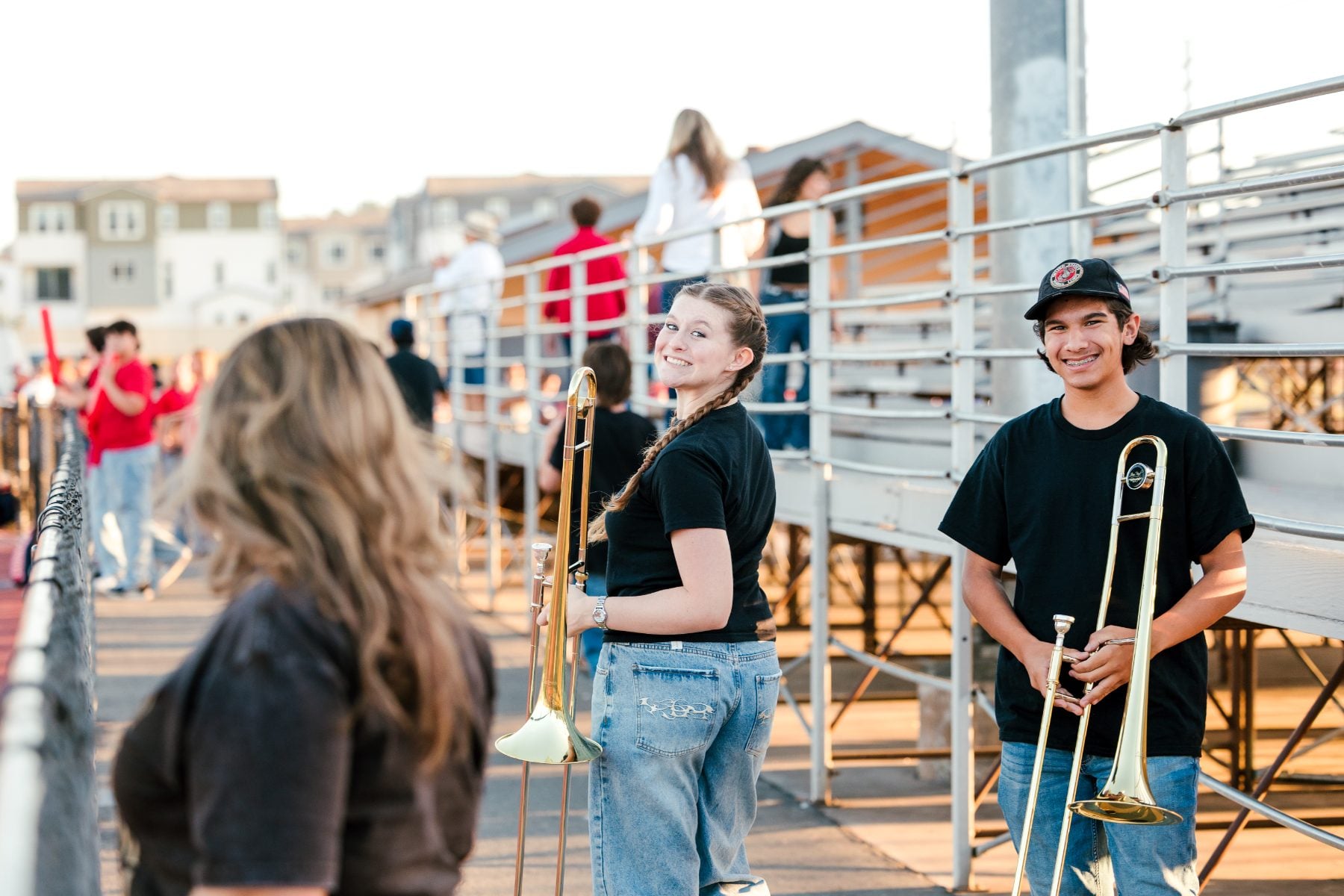 Band students hold trombones while chatting on the bleachers