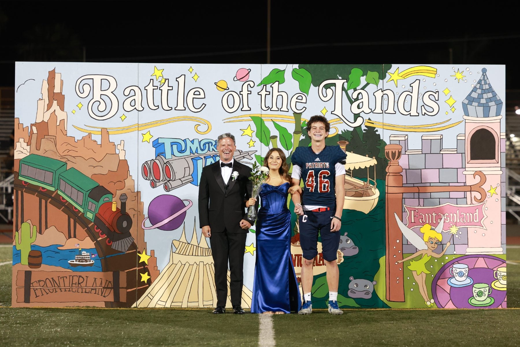 Family poses before Battle of the Lands backdrop at homecoming