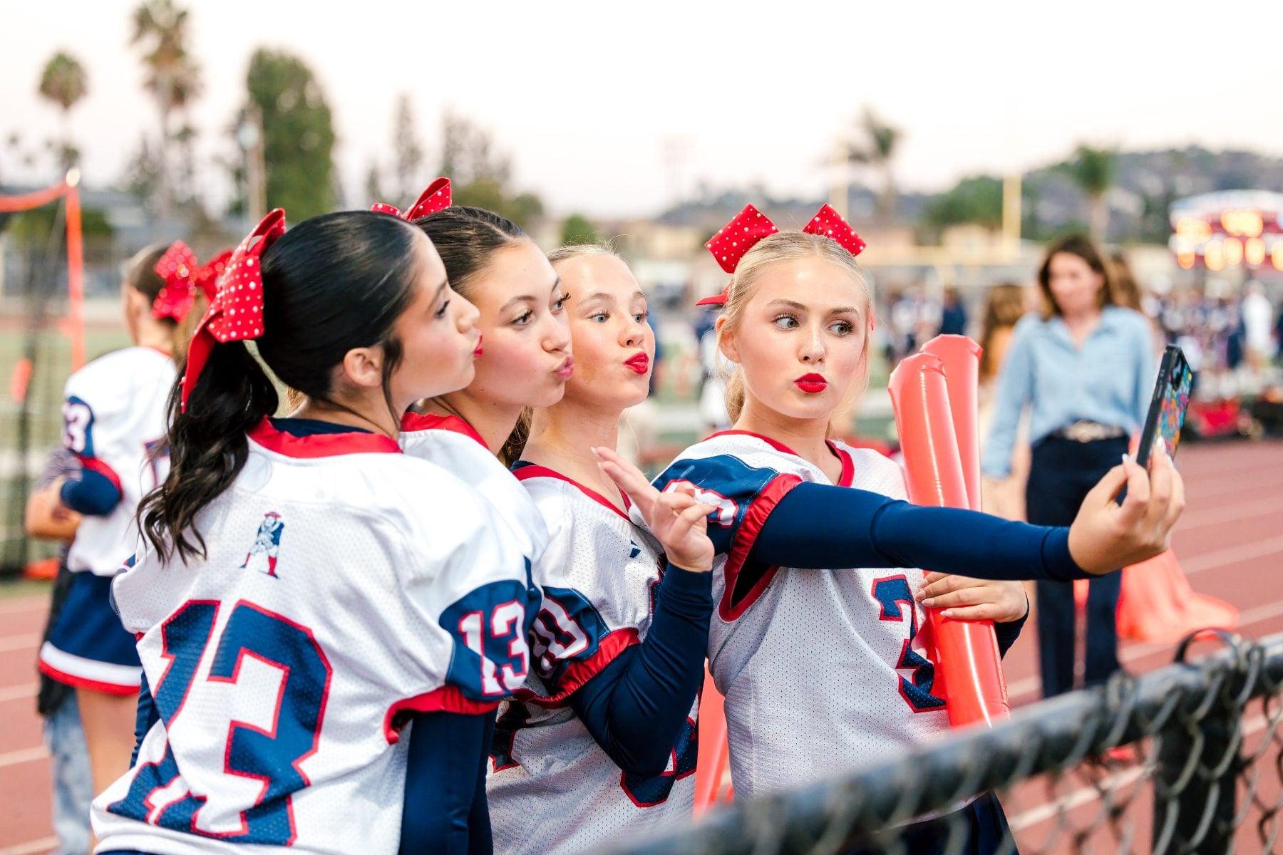 Cheerleaders in Patriots jerseys take a group selfie at homecoming night
