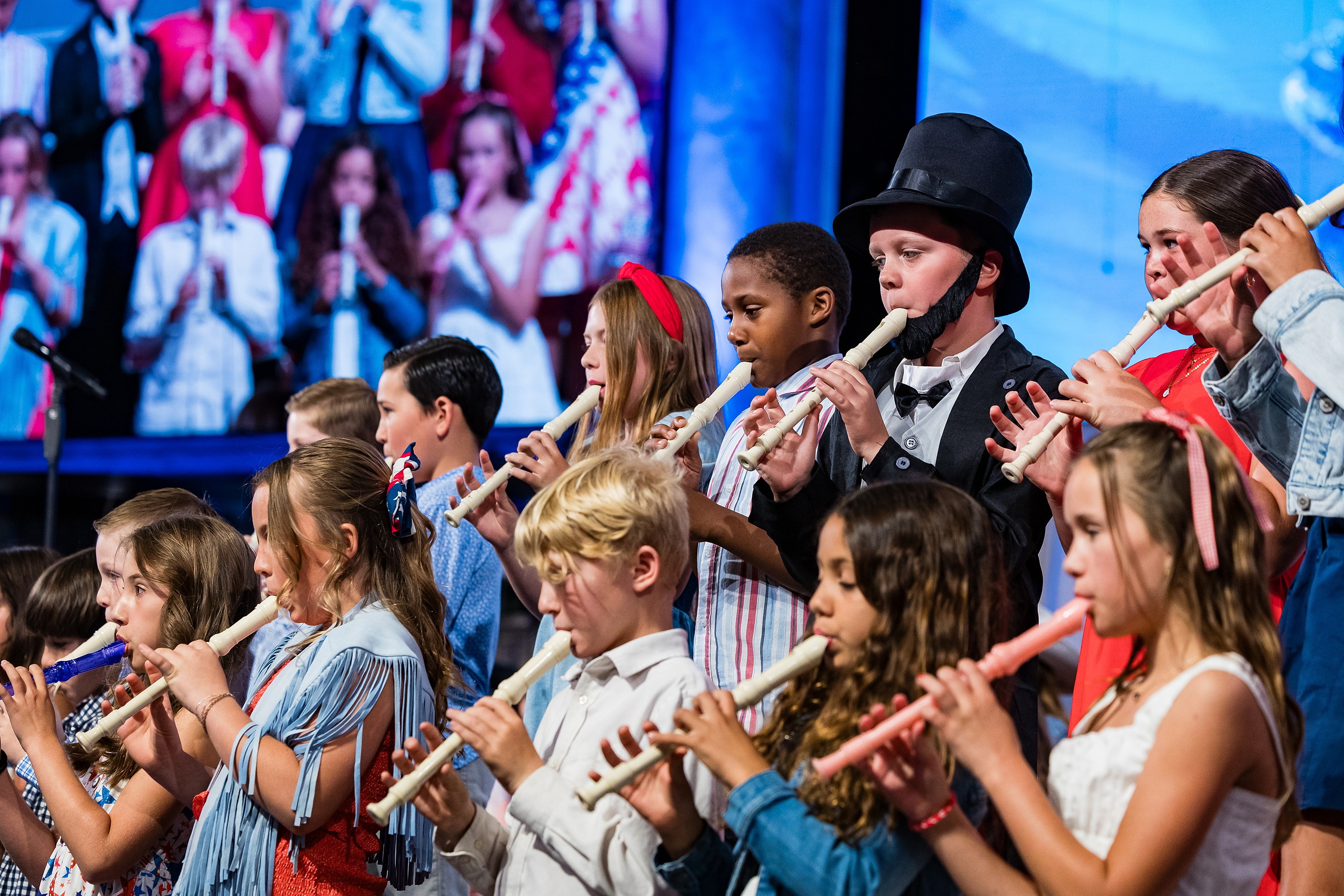 Christian Elementary East Celebrates Spring with “One Nation Under God” — 08 Students of mixed grades playing recorders and singing together on stage